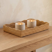Woven tray with two candles on a wooden surface