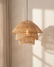 Woven rattan pendant light hanging against a neutral wall with soft shadows.