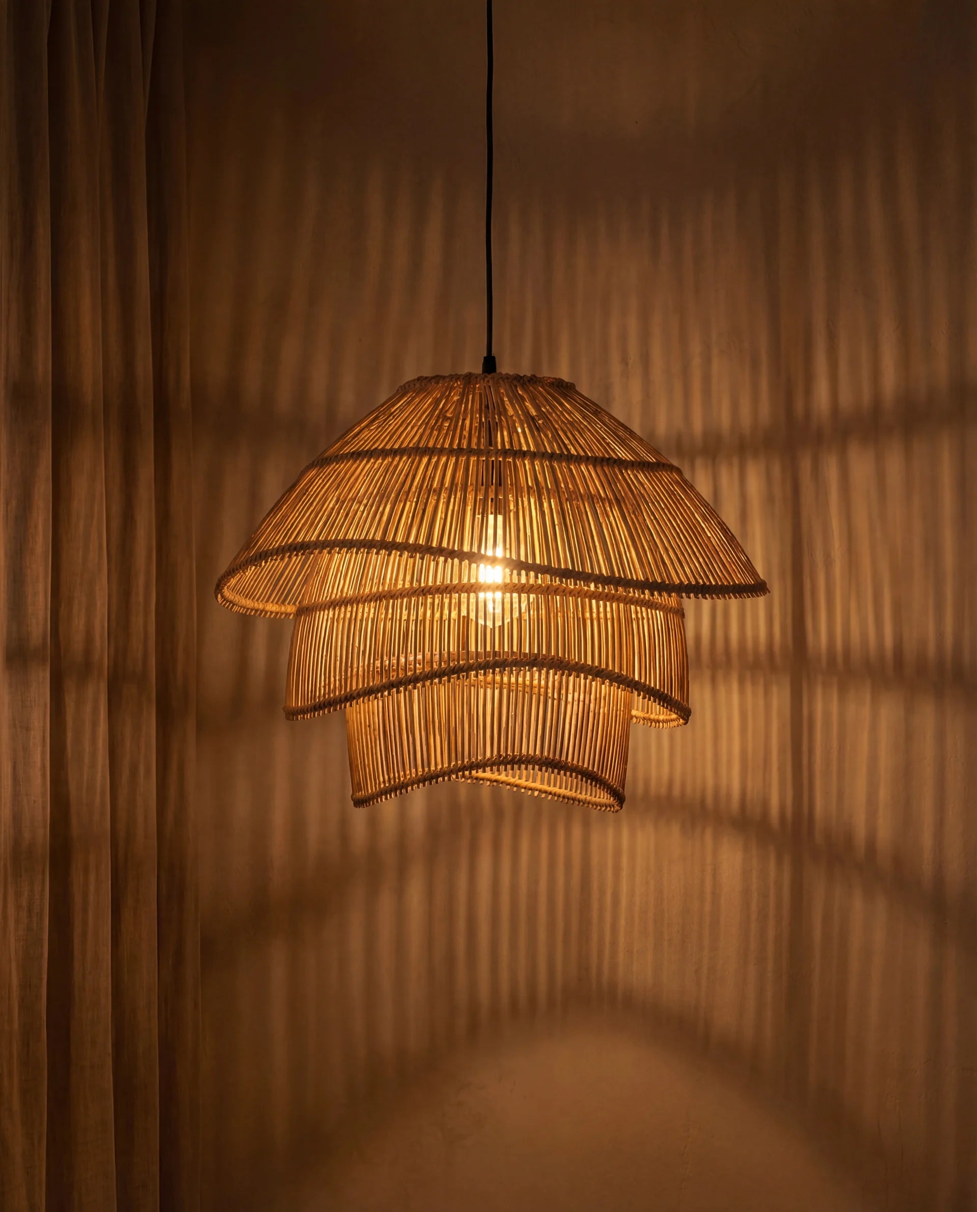 Woven rattan pendant light casting shadows on a wall