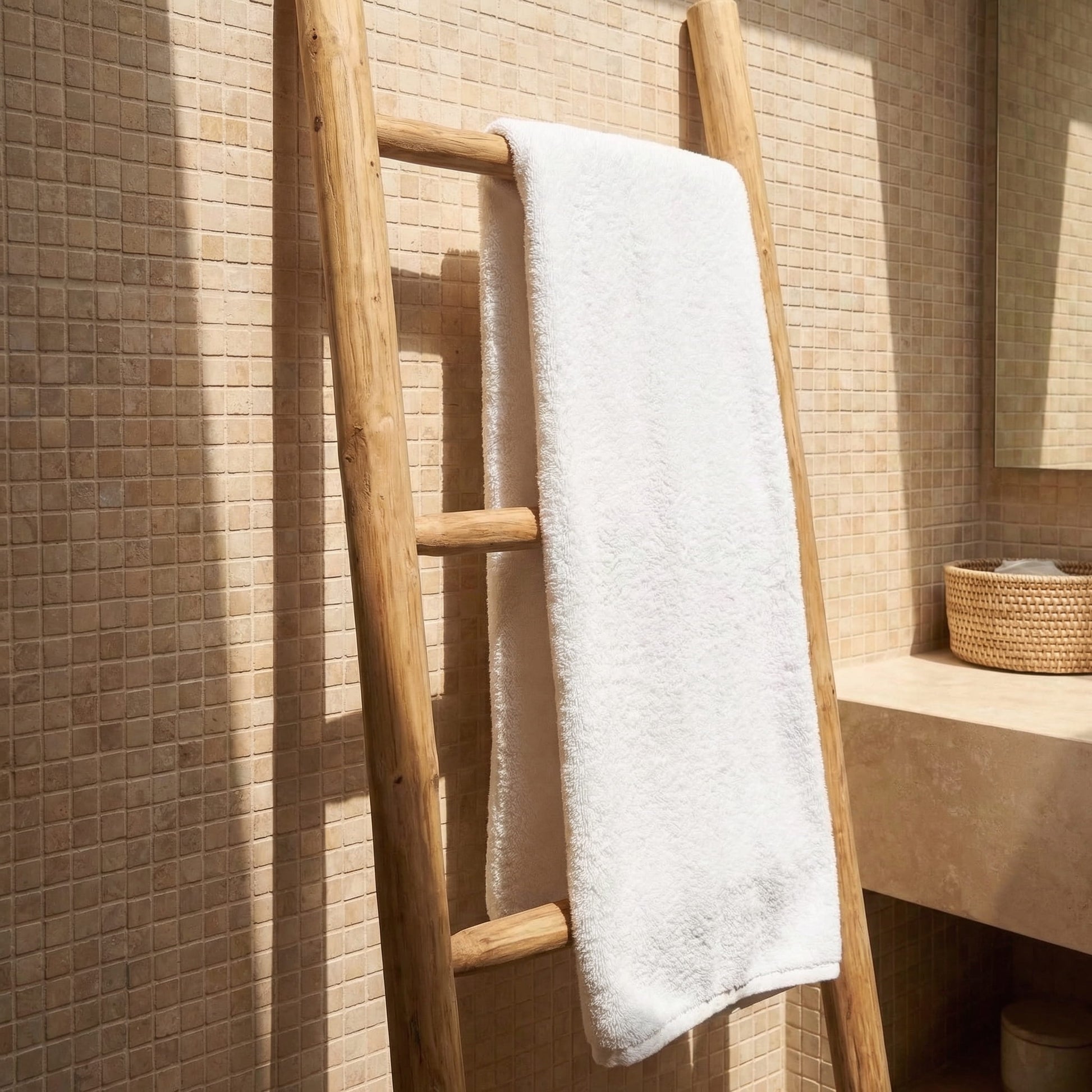 Wooden towel rack with a white towel against a tiled bathroom wall.