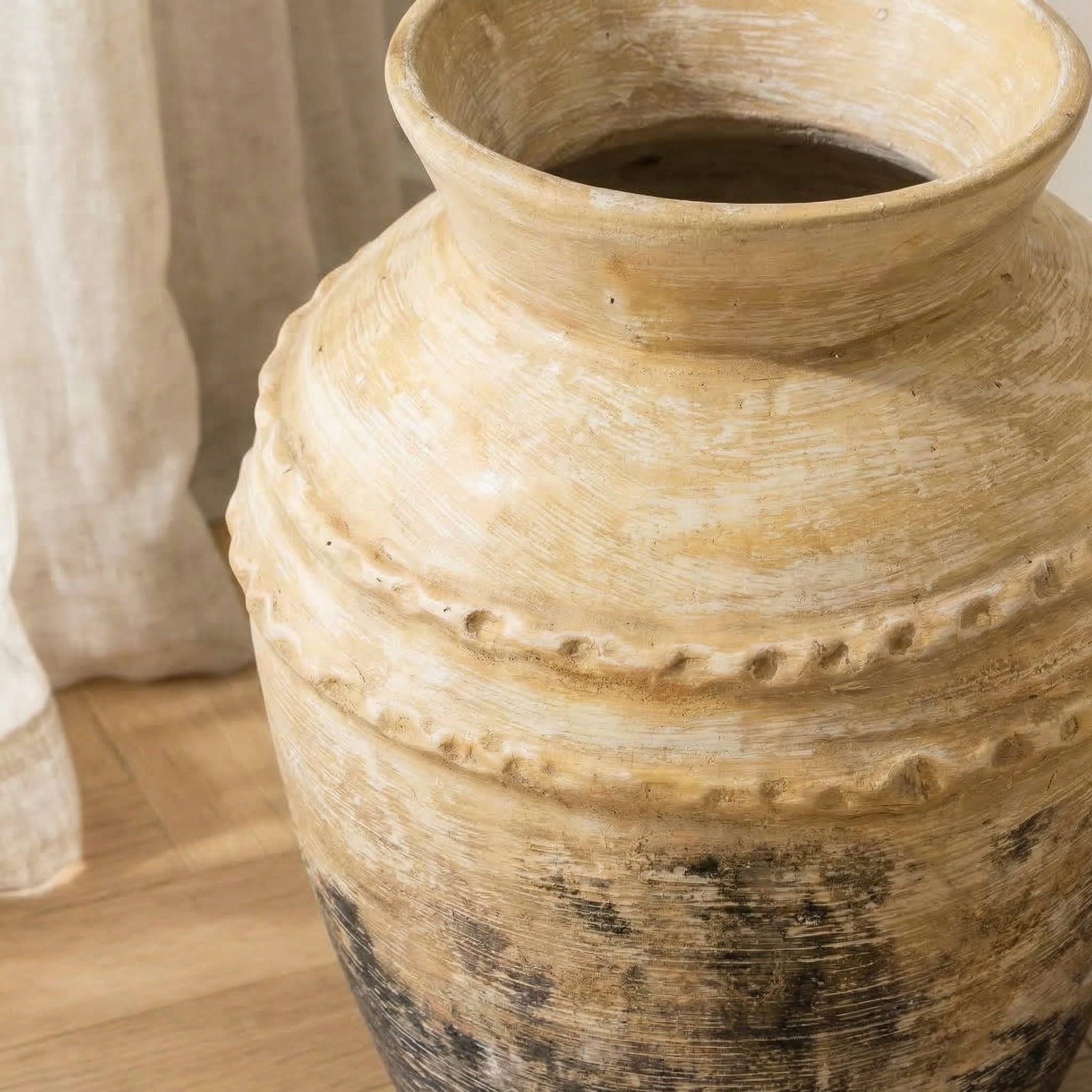 Close-up of a textured ceramic vase on a wooden surface with a neutral background