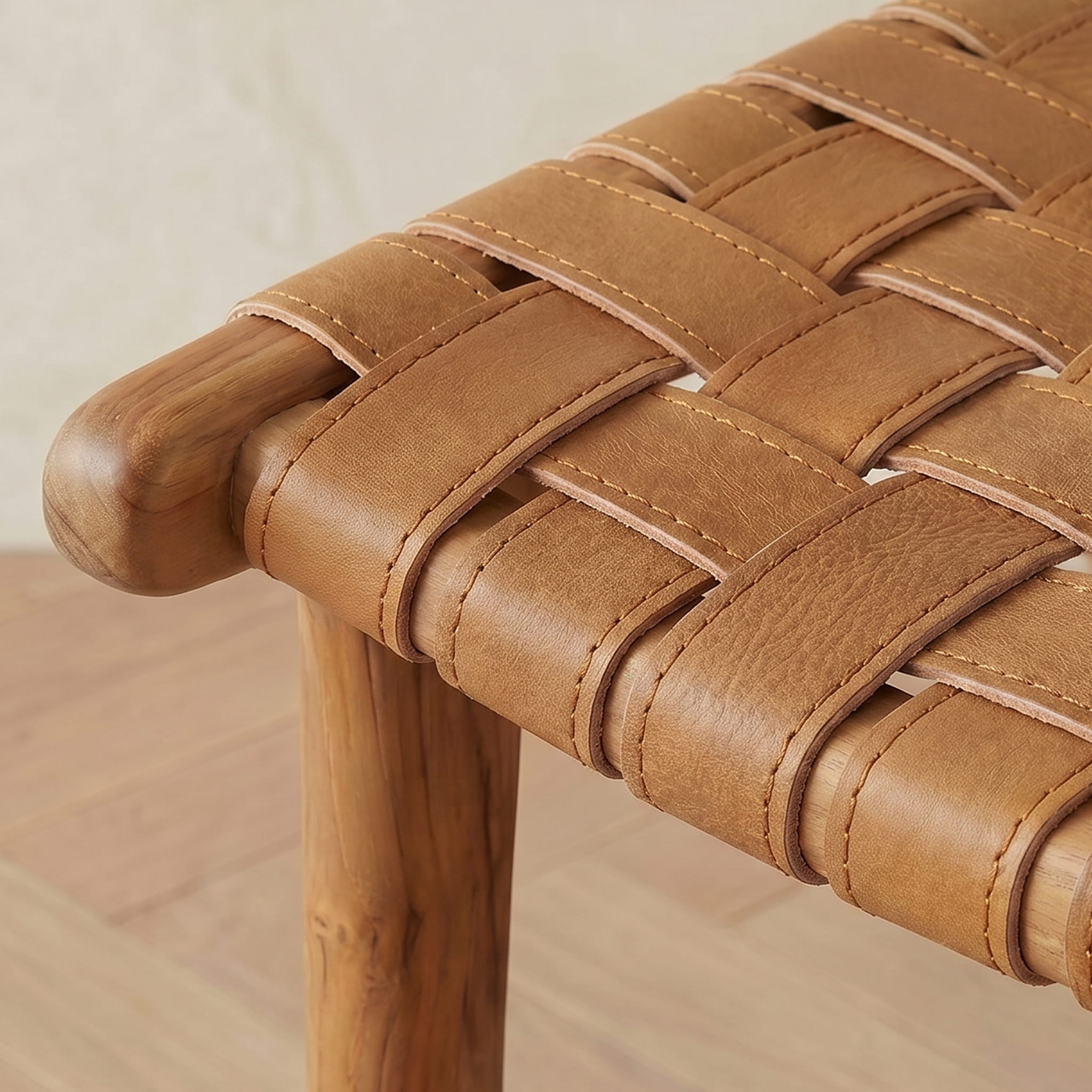 Close-up of a woven brown leather bar stool with wooden armrests on a light background