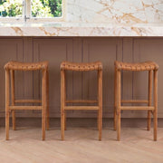 Three leather wooden bar stools in a kitchen setting with marble backsplash and wooden floor.