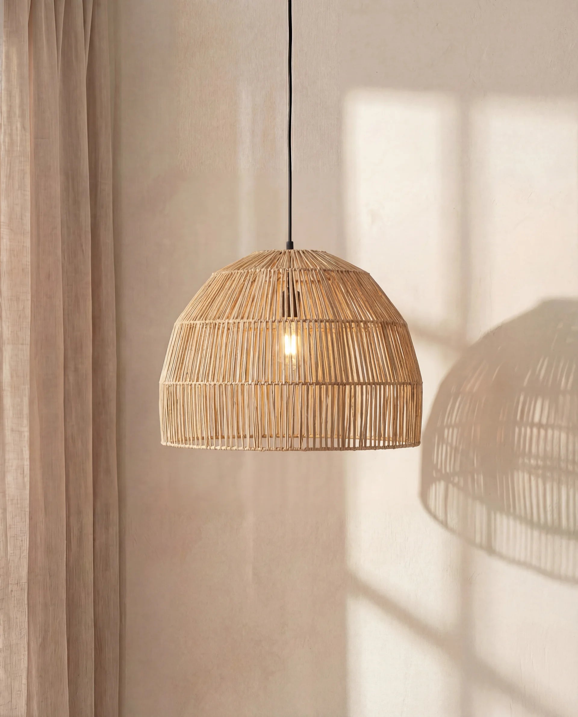 Woven pendant light hanging against a neutral wall with soft shadows.