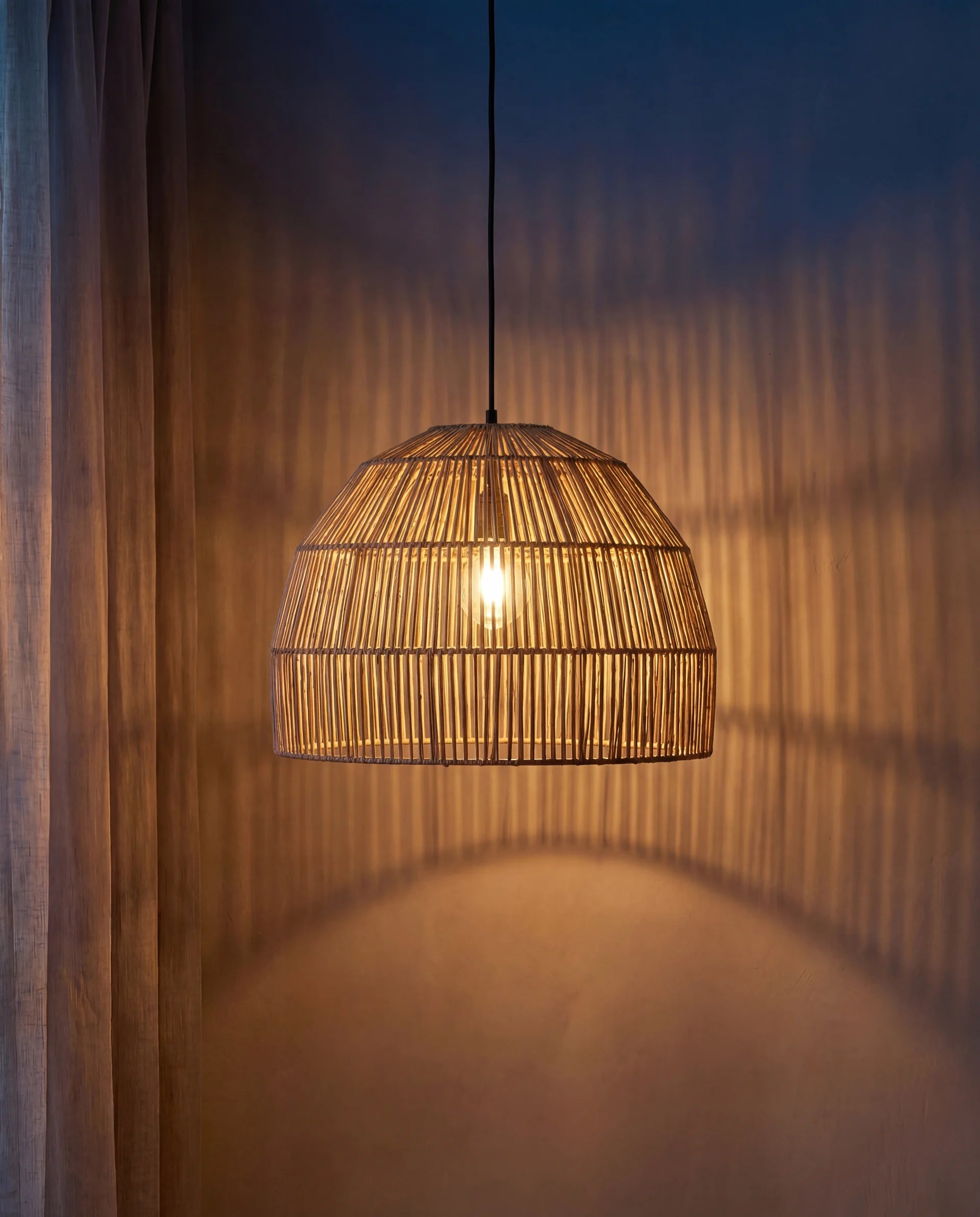 Woven pendant light hanging against a textured wall