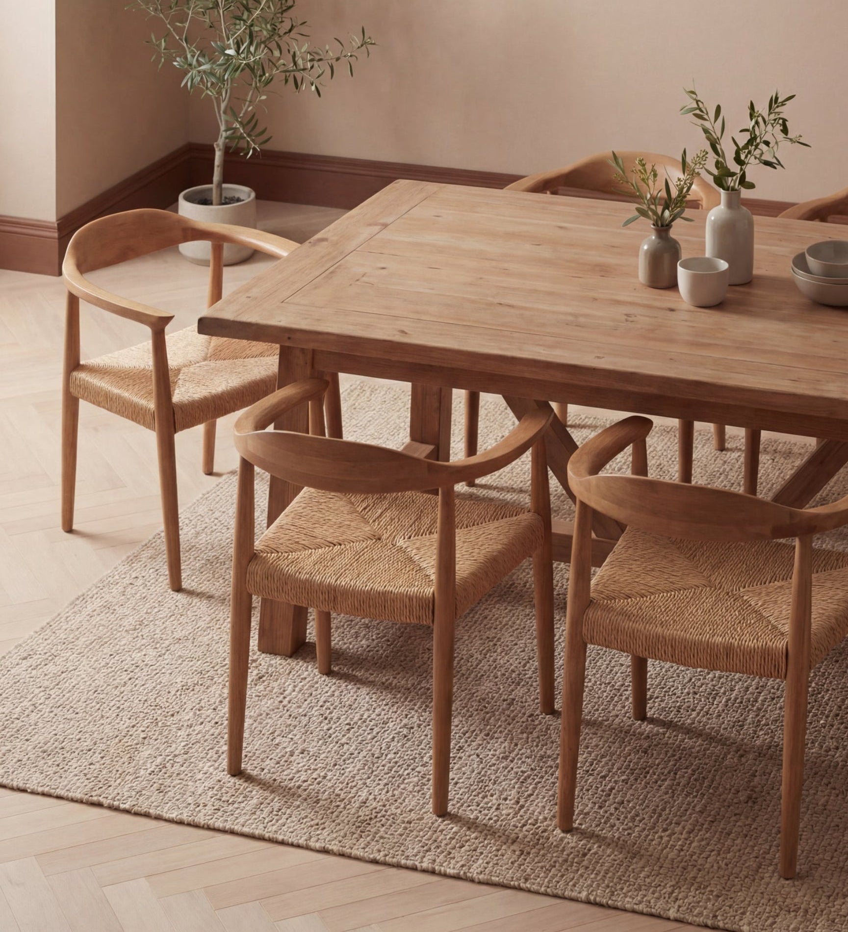 Wooden dining table with chairs in a room with a plant and bowls on the table.