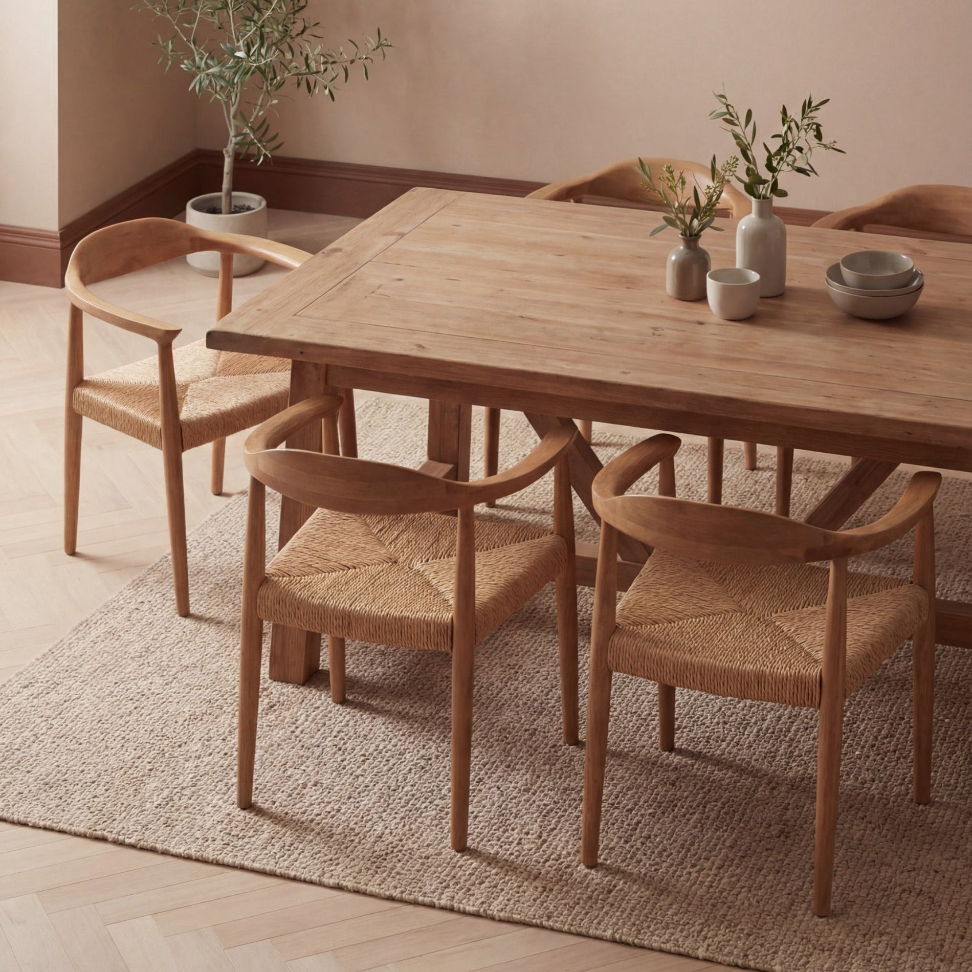 Wooden dining table with chairs in a room with a plant and bowls on the table.