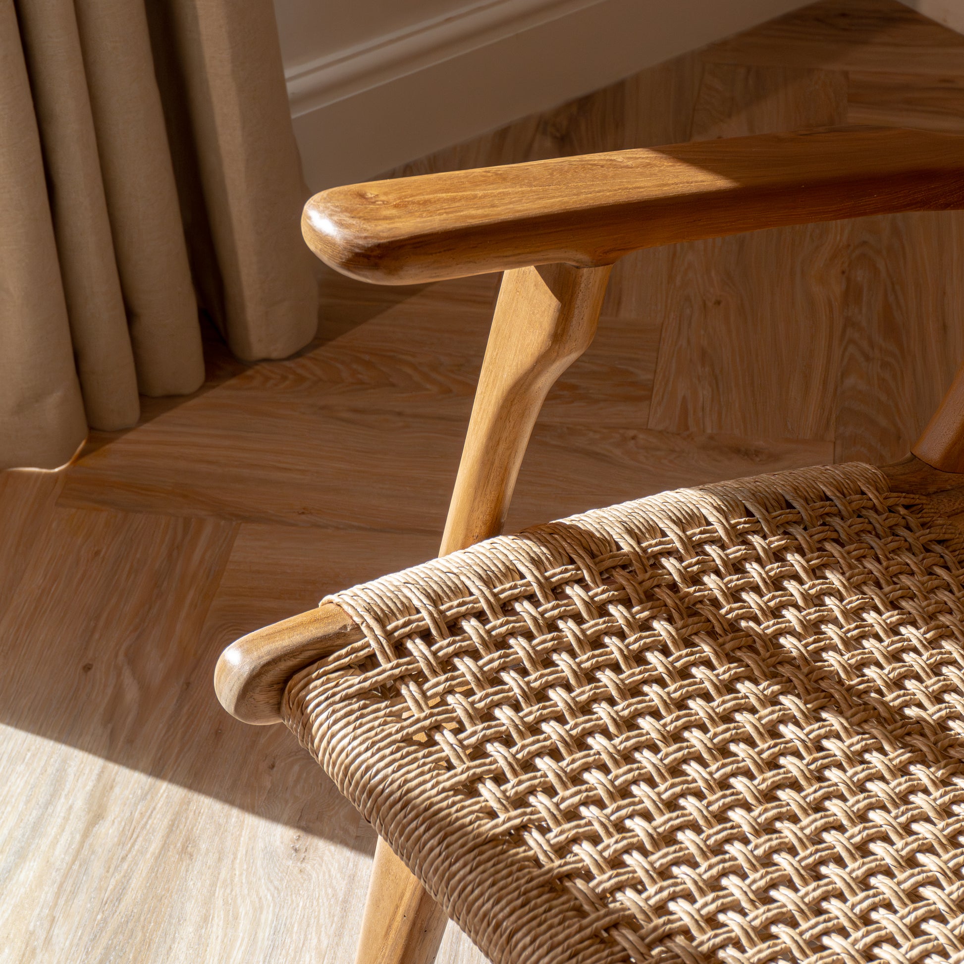 Close-up of a wooden accent chair arm and woven seat