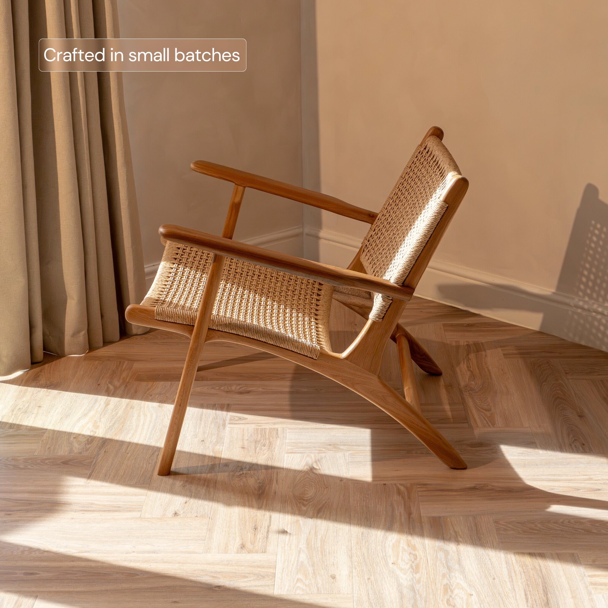 Rattan accent chair with wicker back and seat in a room with sunlight streaming through curtains