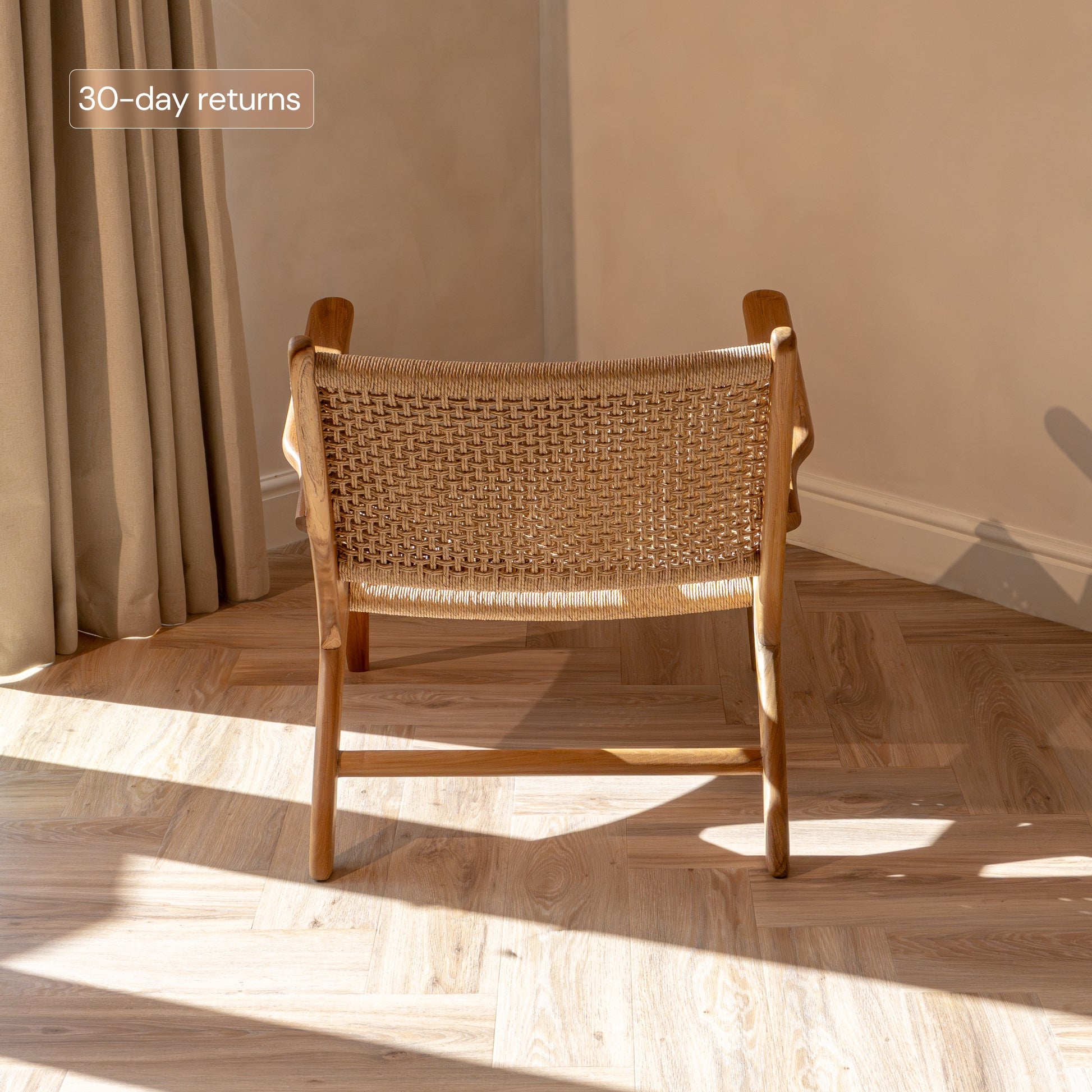 Rattan accent chair with wicker back and seat in a room with sunlight streaming through curtains