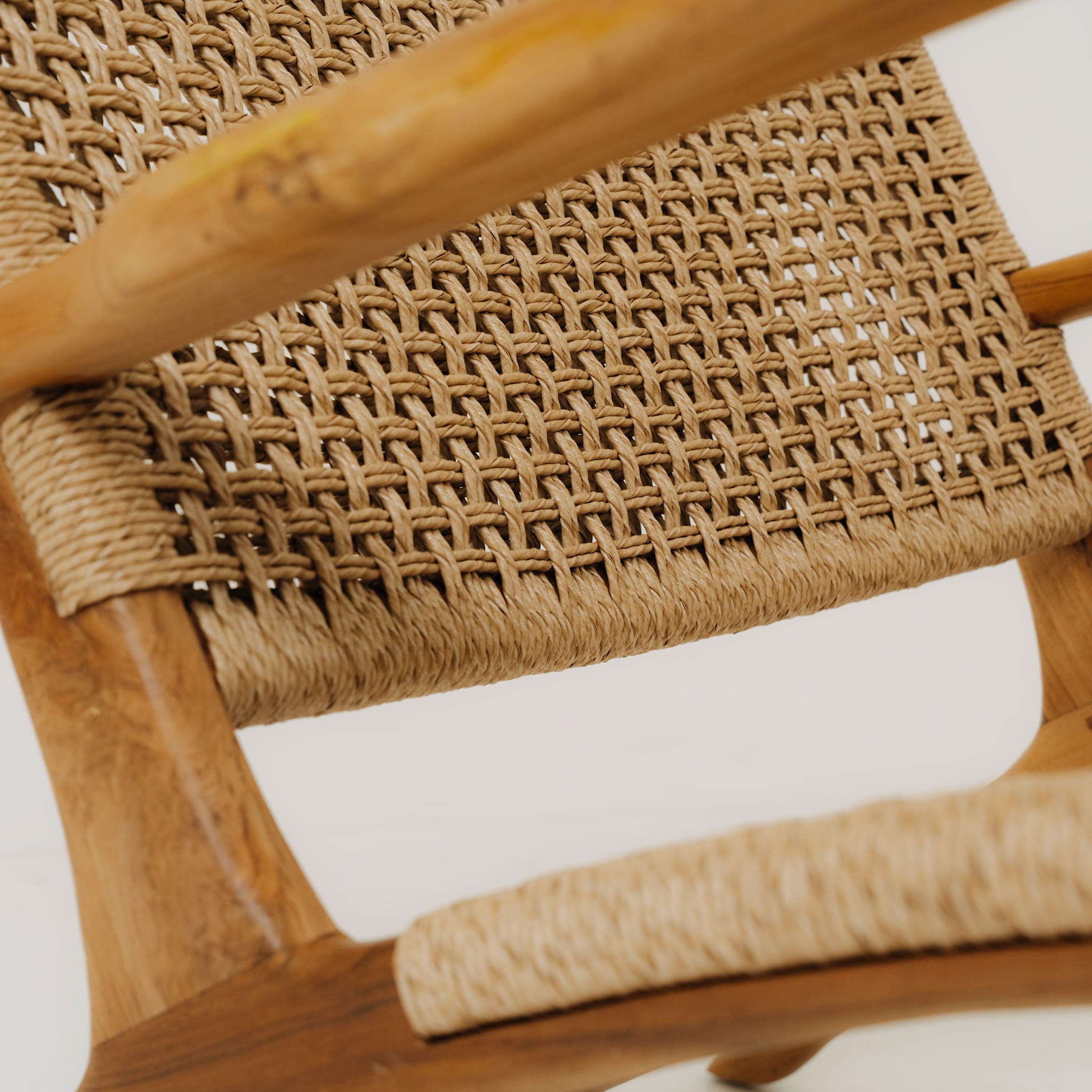 Close-up of a woven chair seat with natural wood frame on a white background
