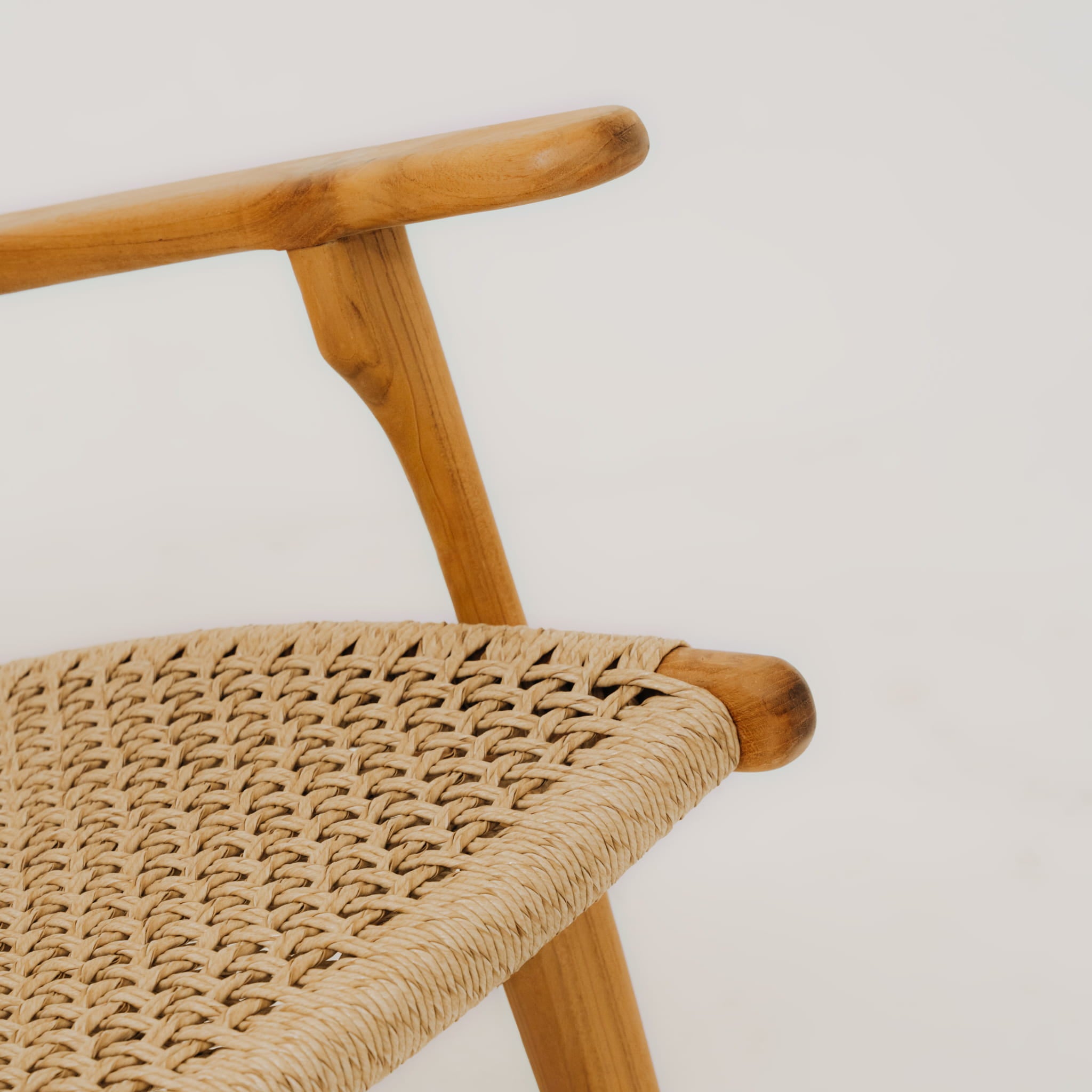 Close-up of a wooden chair with woven seat on a light background