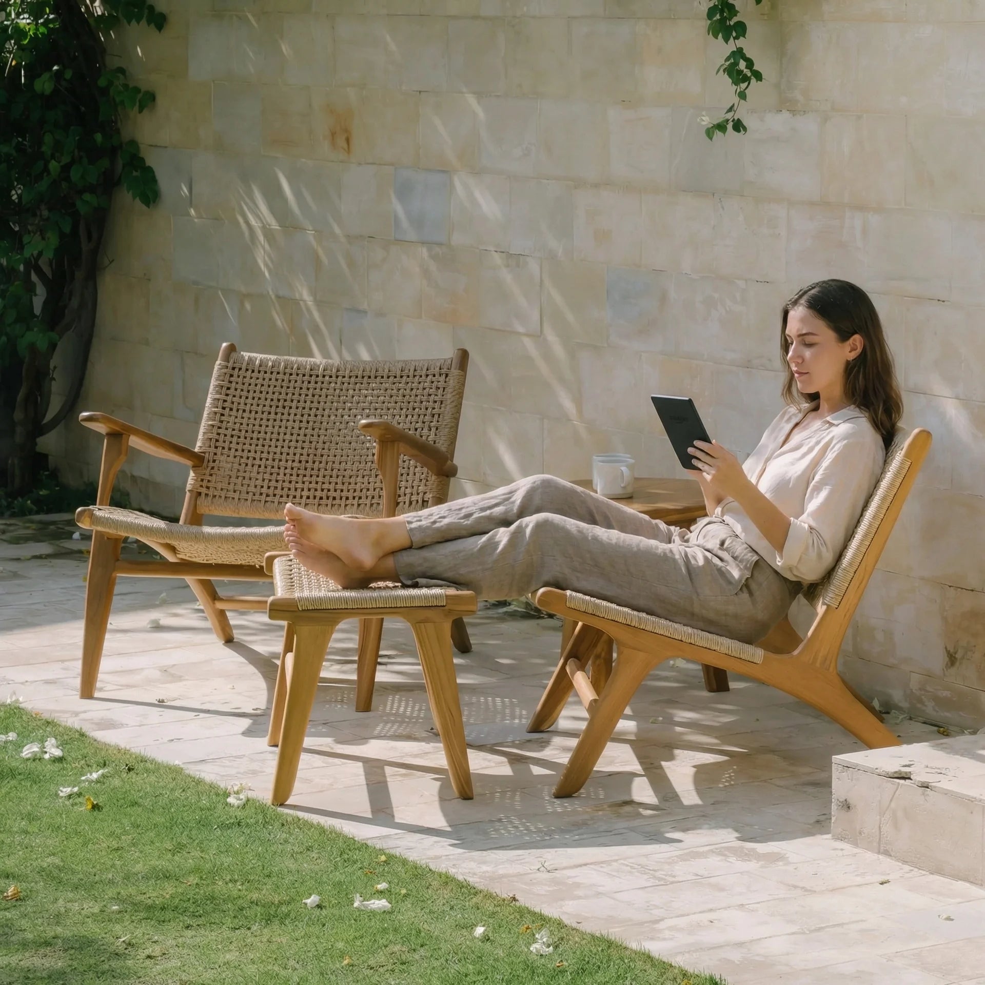 Woman reading a book in a garden setting with wooden furniture.