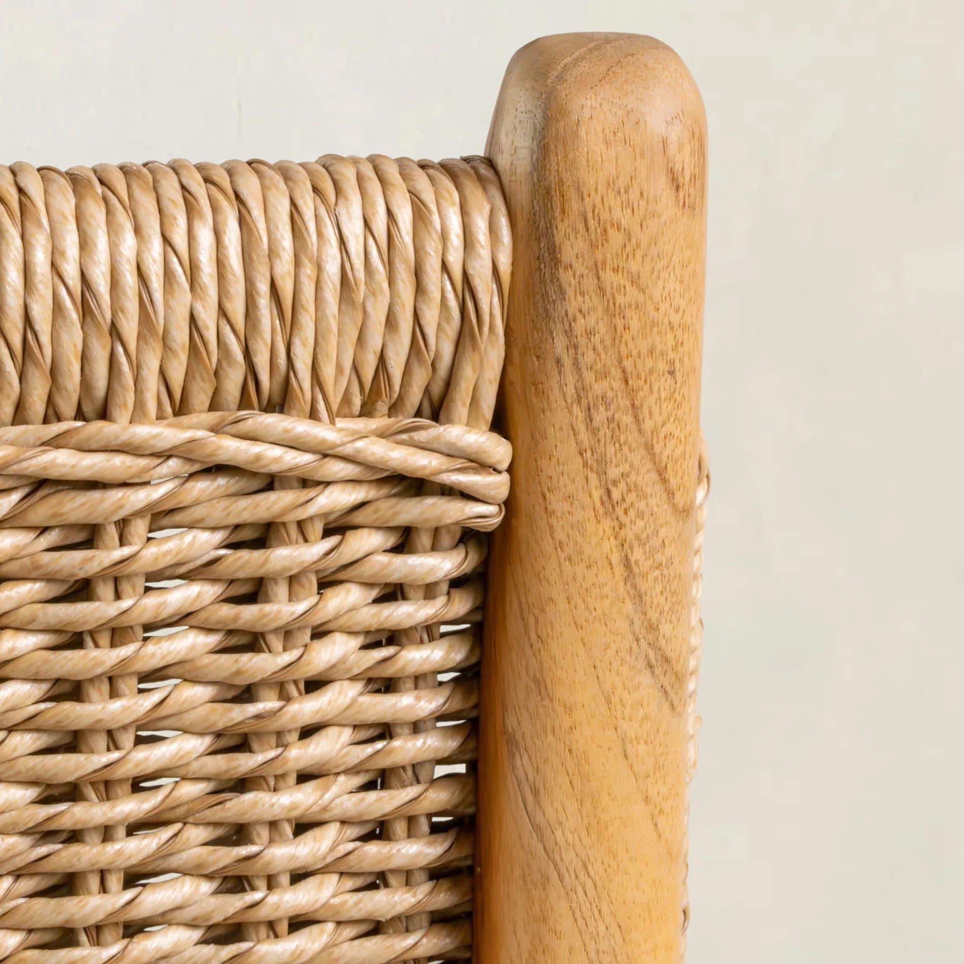 Close-up of a wicker chair with wooden armrest on a plain background
