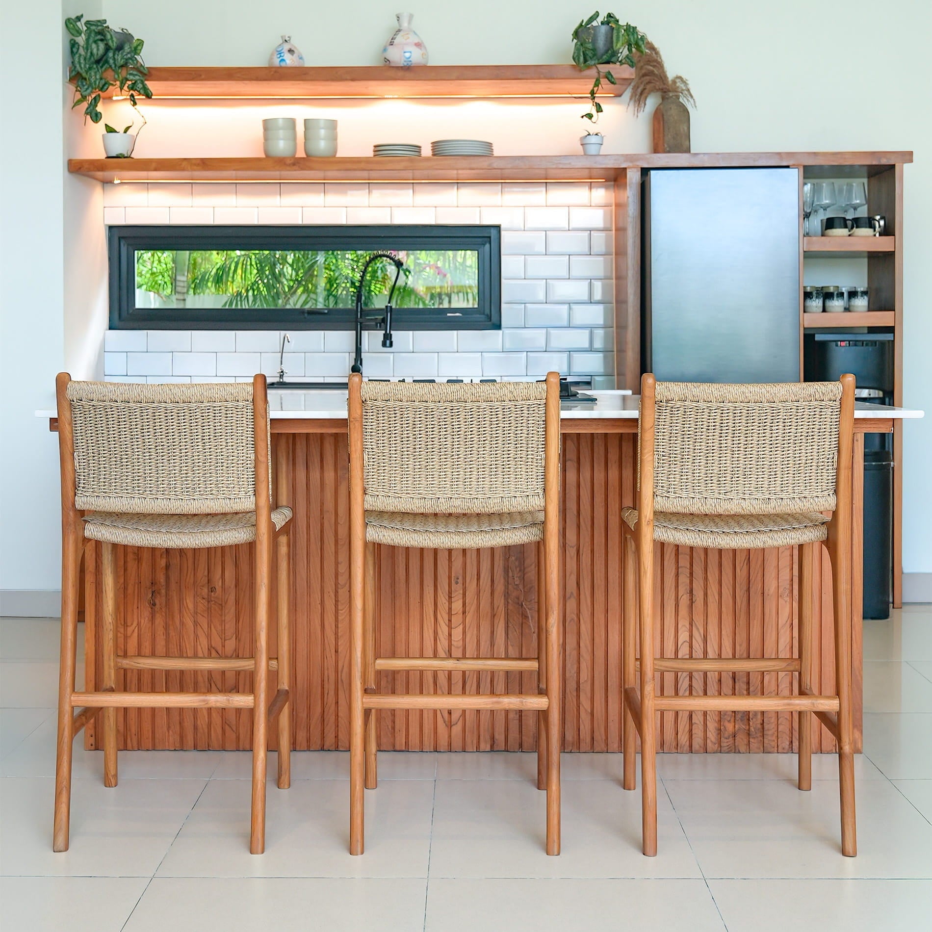 Three wooden rattan bar stools with rattan backrests in front of a kitchen counter.