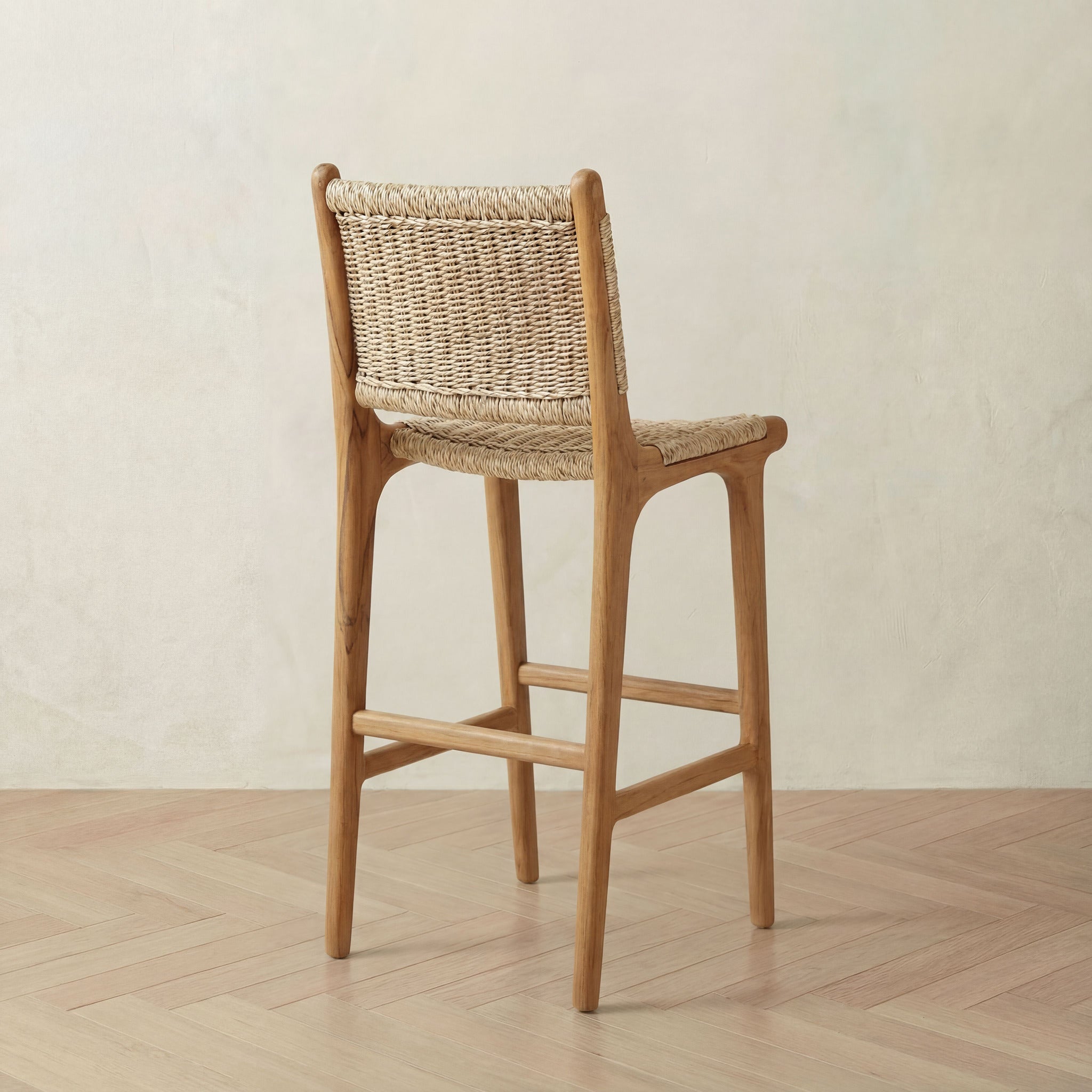 Wooden bar stool with wicker backrest on a wooden floor against a beige wall