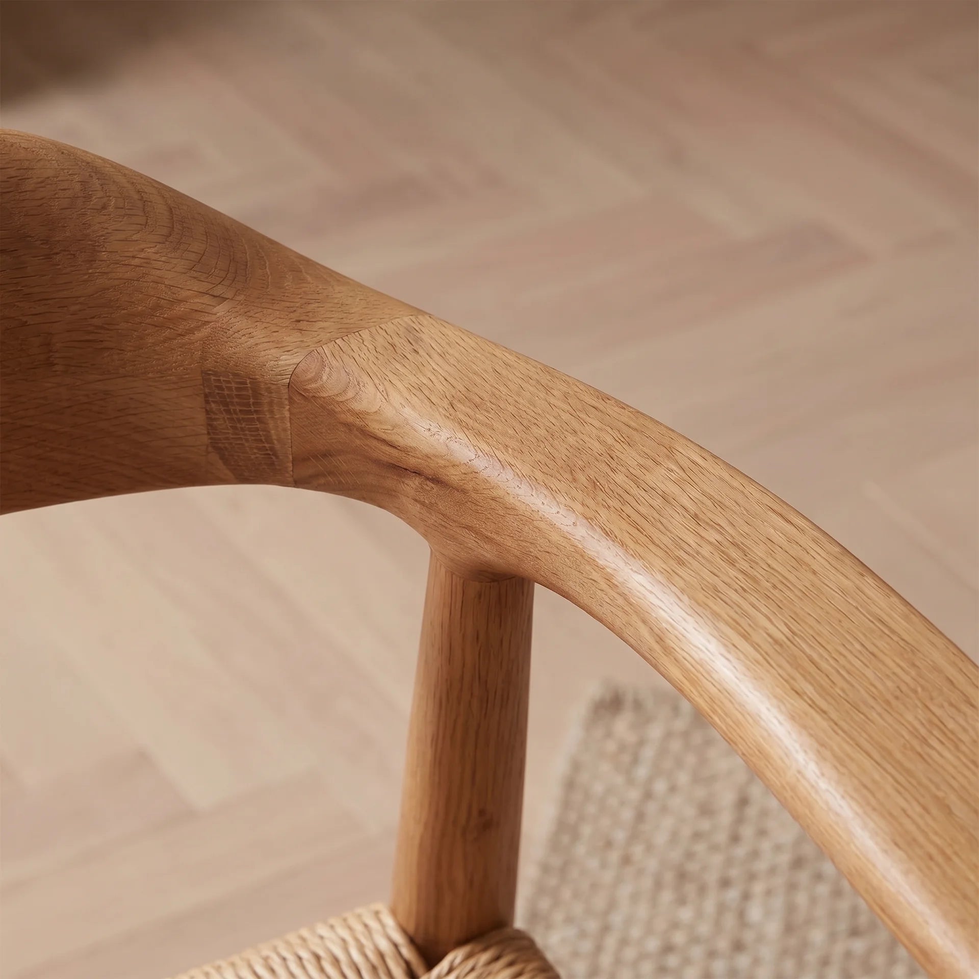 Close-up of a wooden chair arm on a blurred wooden floor background