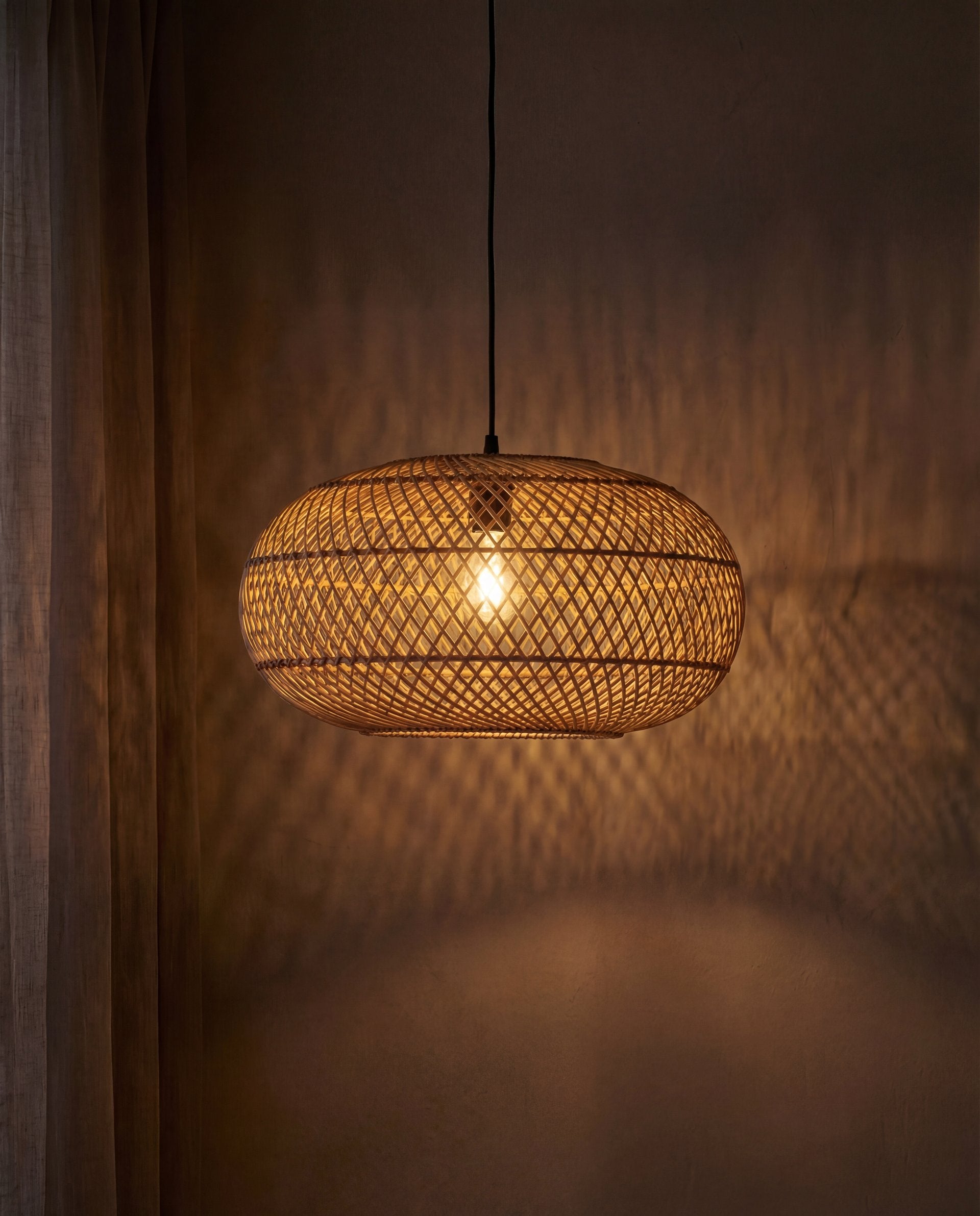 Woven pendant light hanging against a dark background
