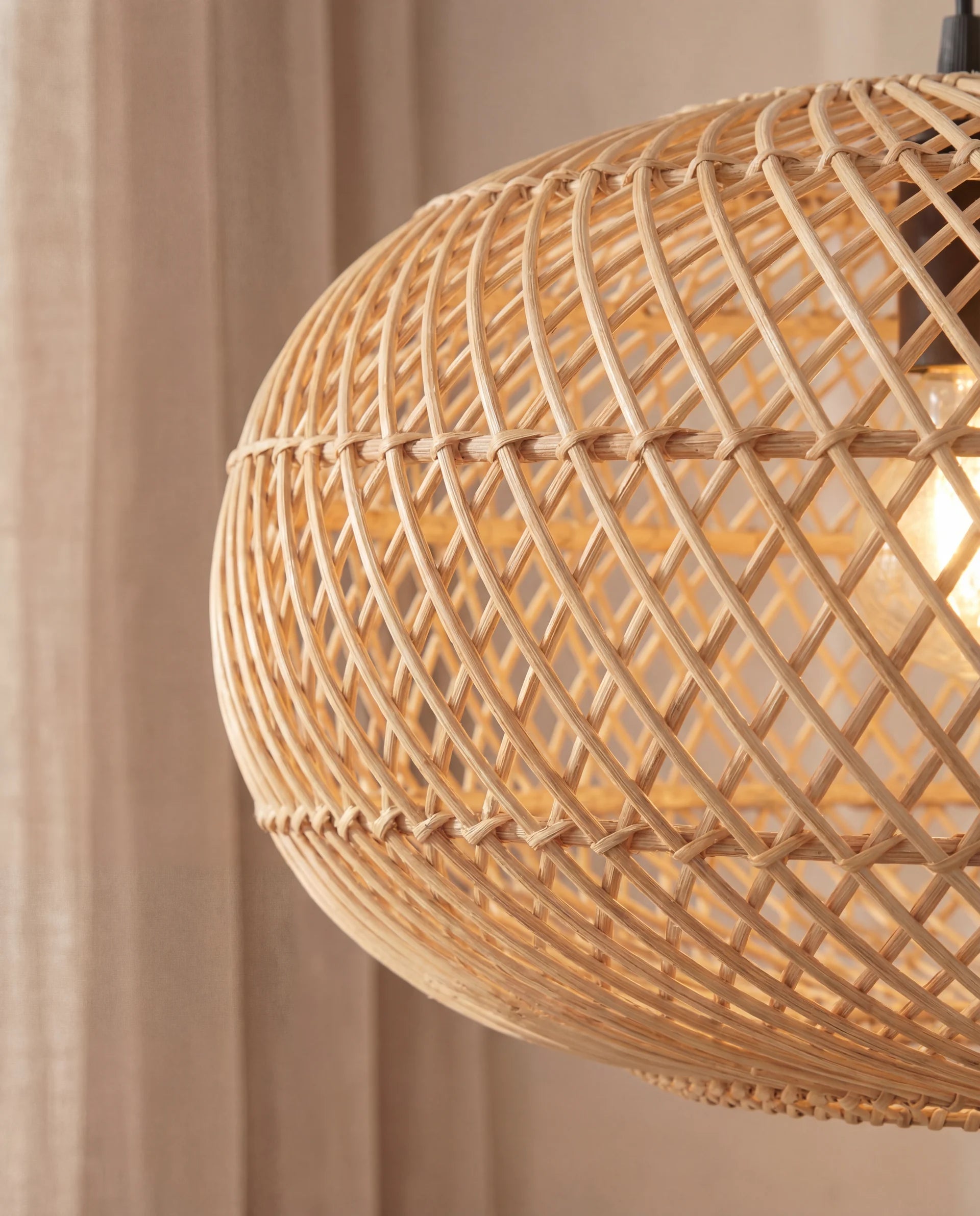Woven rattan pendant light against a neutral background