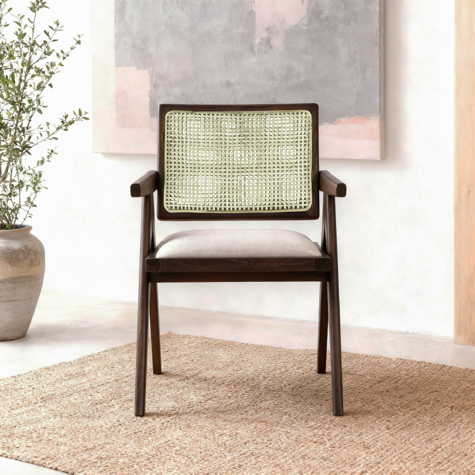 Wooden chair with wicker backrest in a room with a plant and painting.