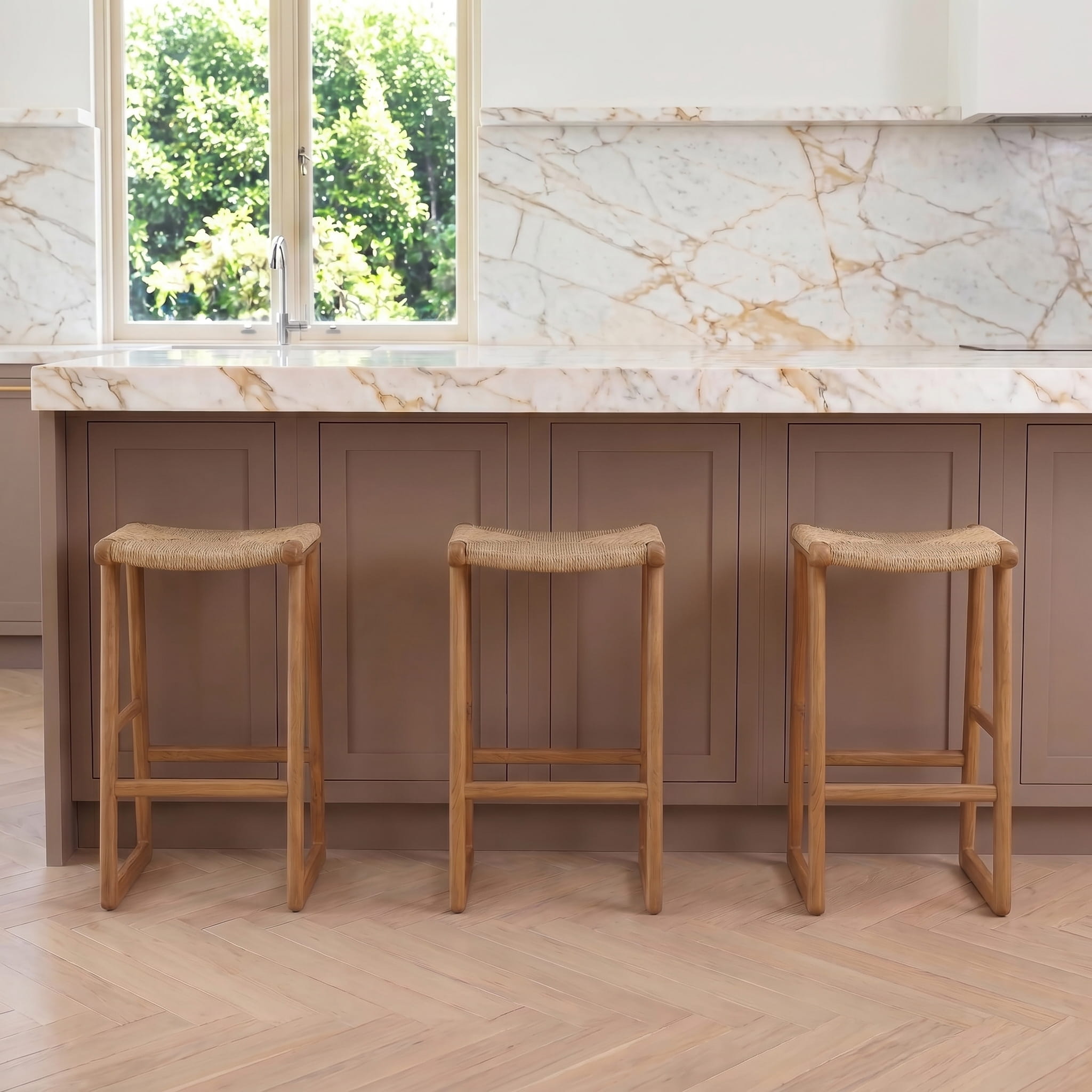 Three wooden bar stools in front of a kitchen counter with marble countertop and window.