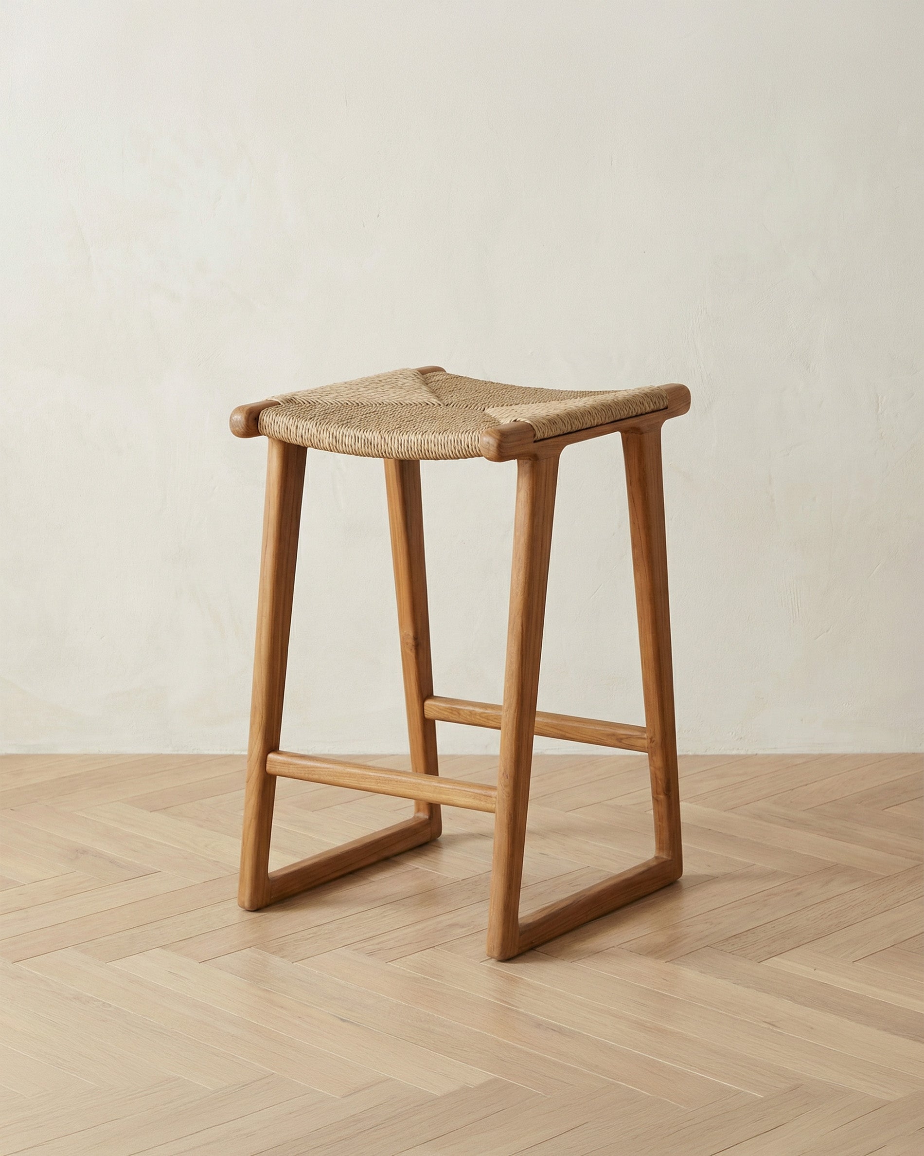 Wooden stool with woven seat on a wooden floor against a beige wall
