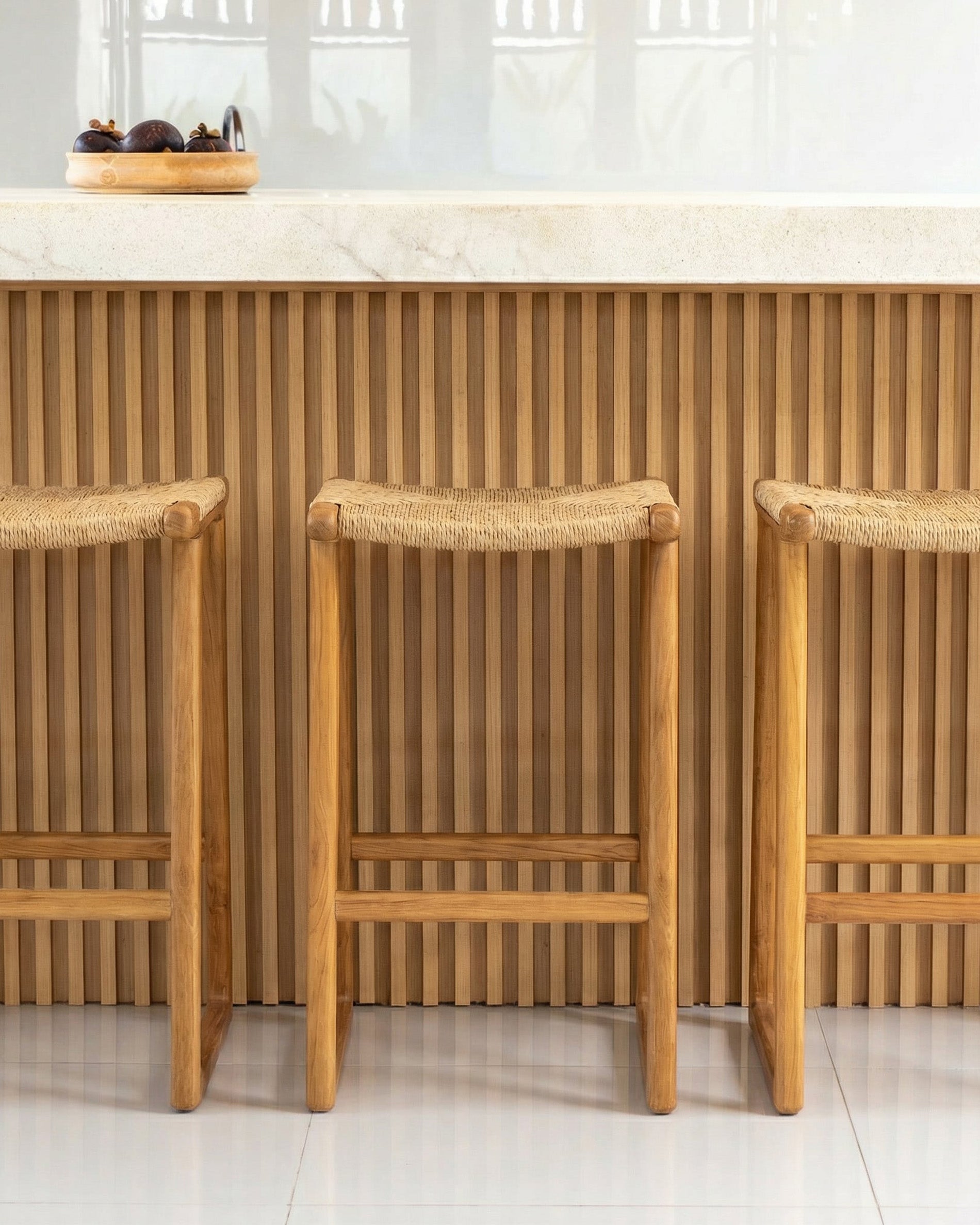 Three wooden bar stools with woven backrests in a kitchen setting.