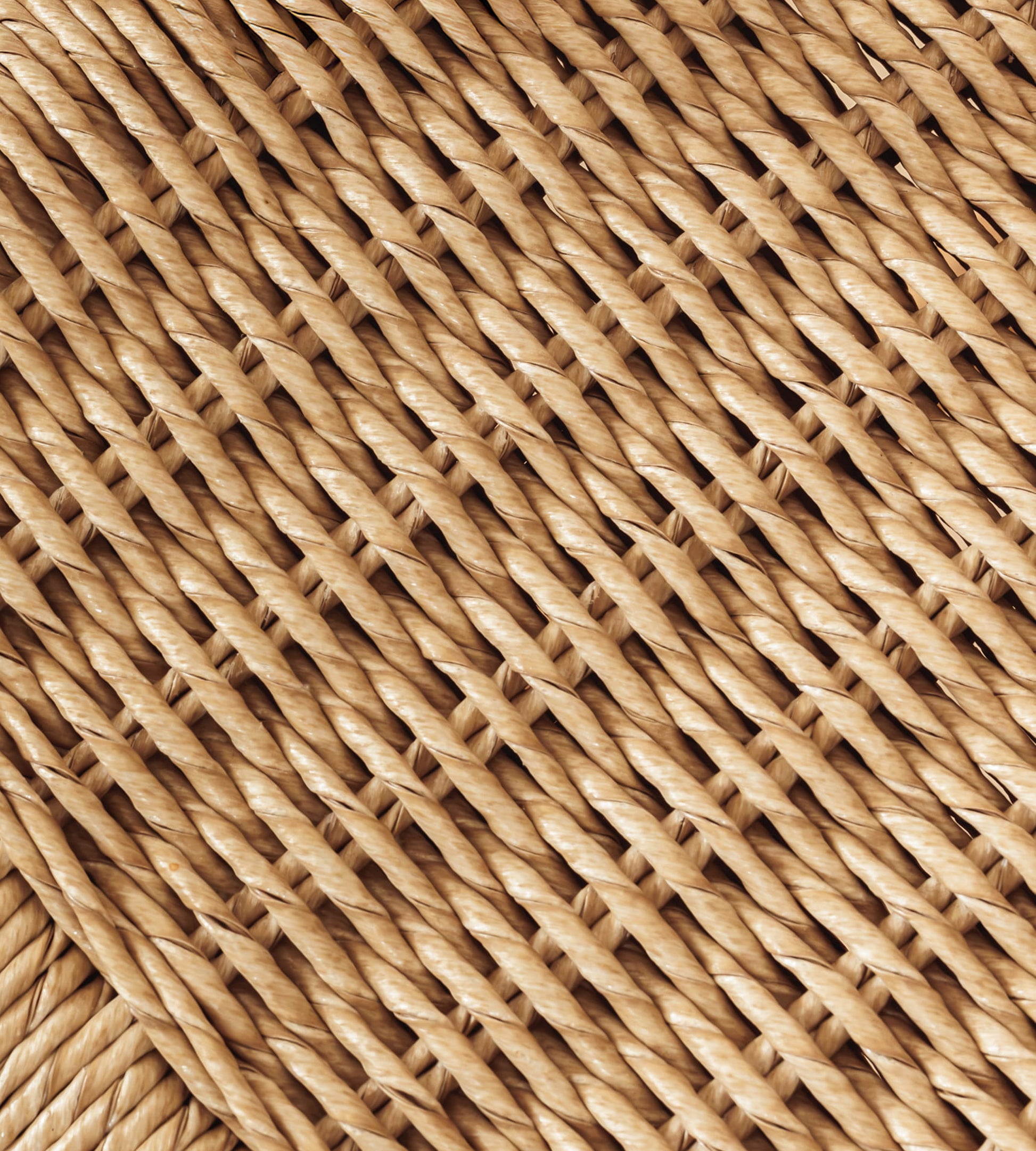 A close-up of a woven natural fiber rattan, wicker, or seagrass, showing a detailed diagonal pattern in warm tan and light brown shades.
