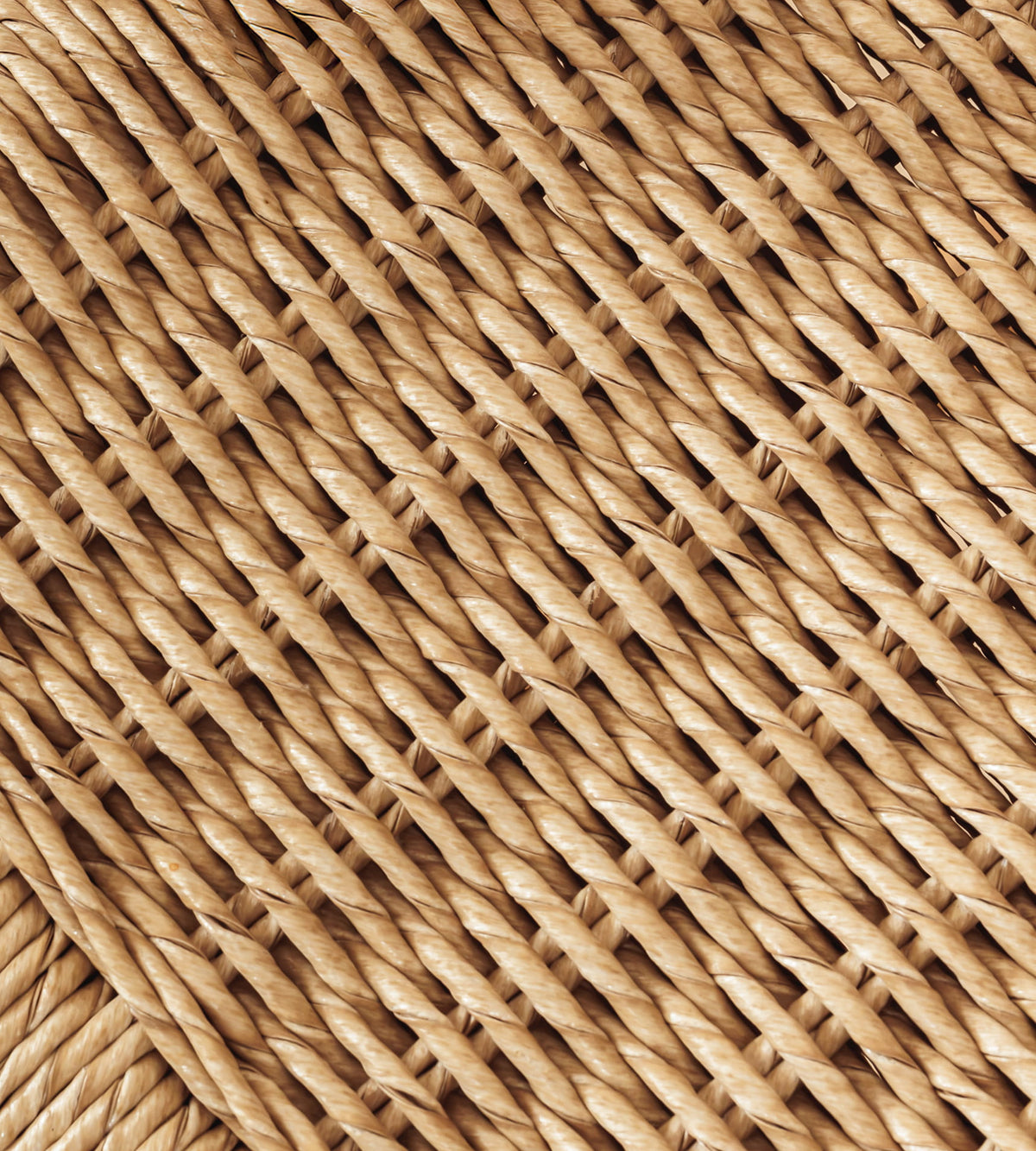 A close-up of a woven natural fiber rattan, wicker, or seagrass, showing a detailed diagonal pattern in warm tan and light brown shades.