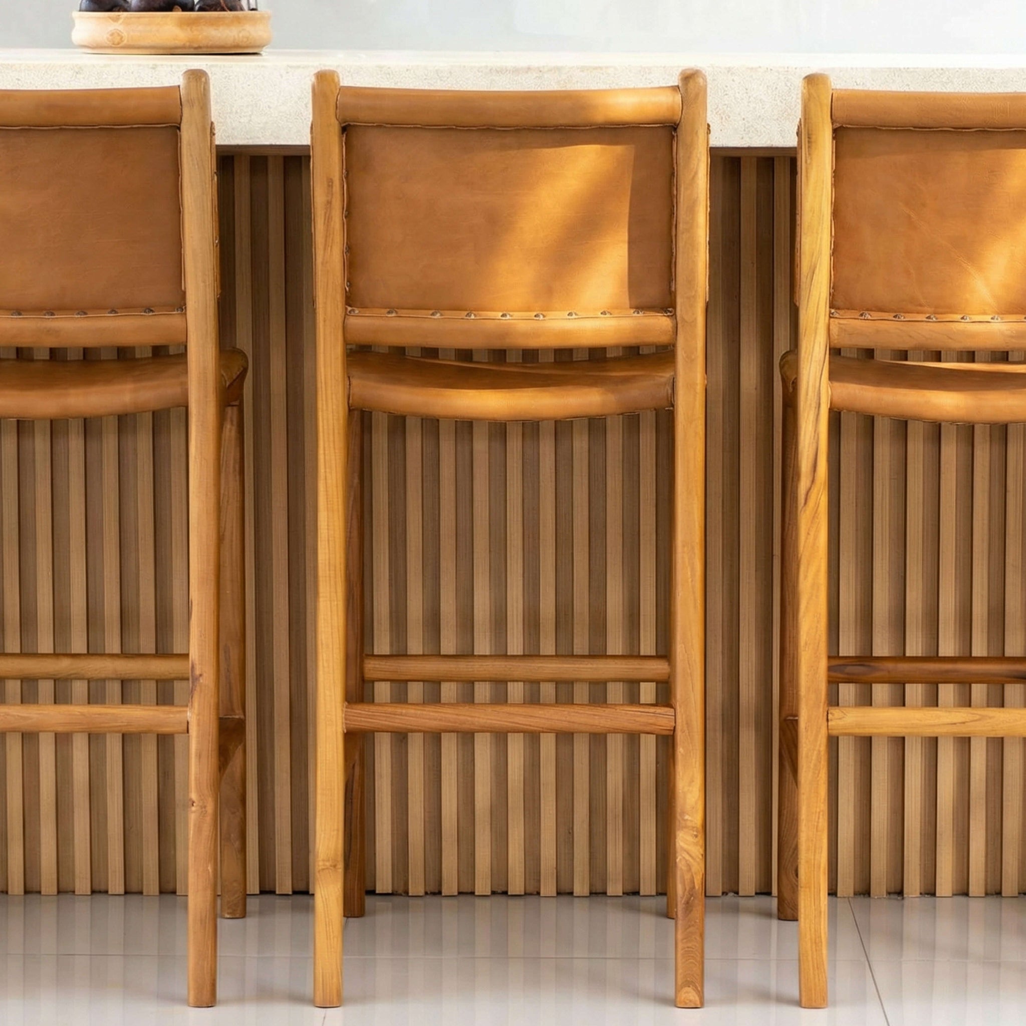 Three wooden bar stools in a kitchen setting with a white countertop.