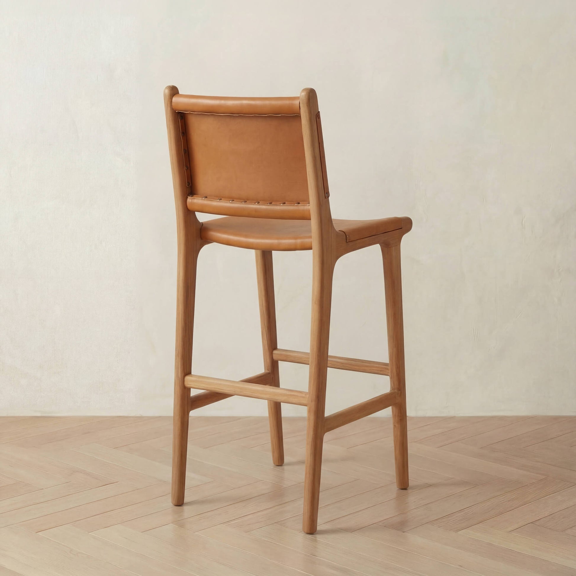 Wooden bar stool with a backrest on a wooden floor against a light wall.