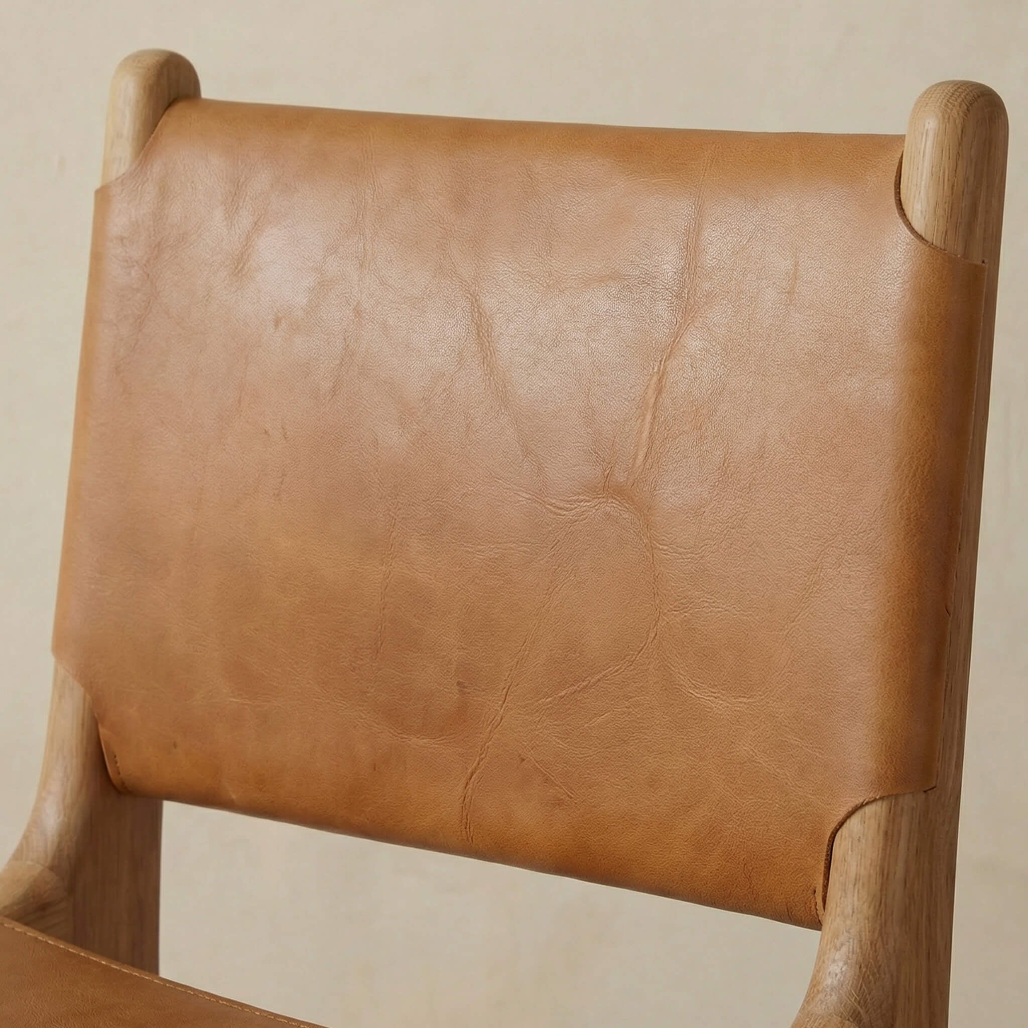 Brown leather chair with wooden armrests on a beige background