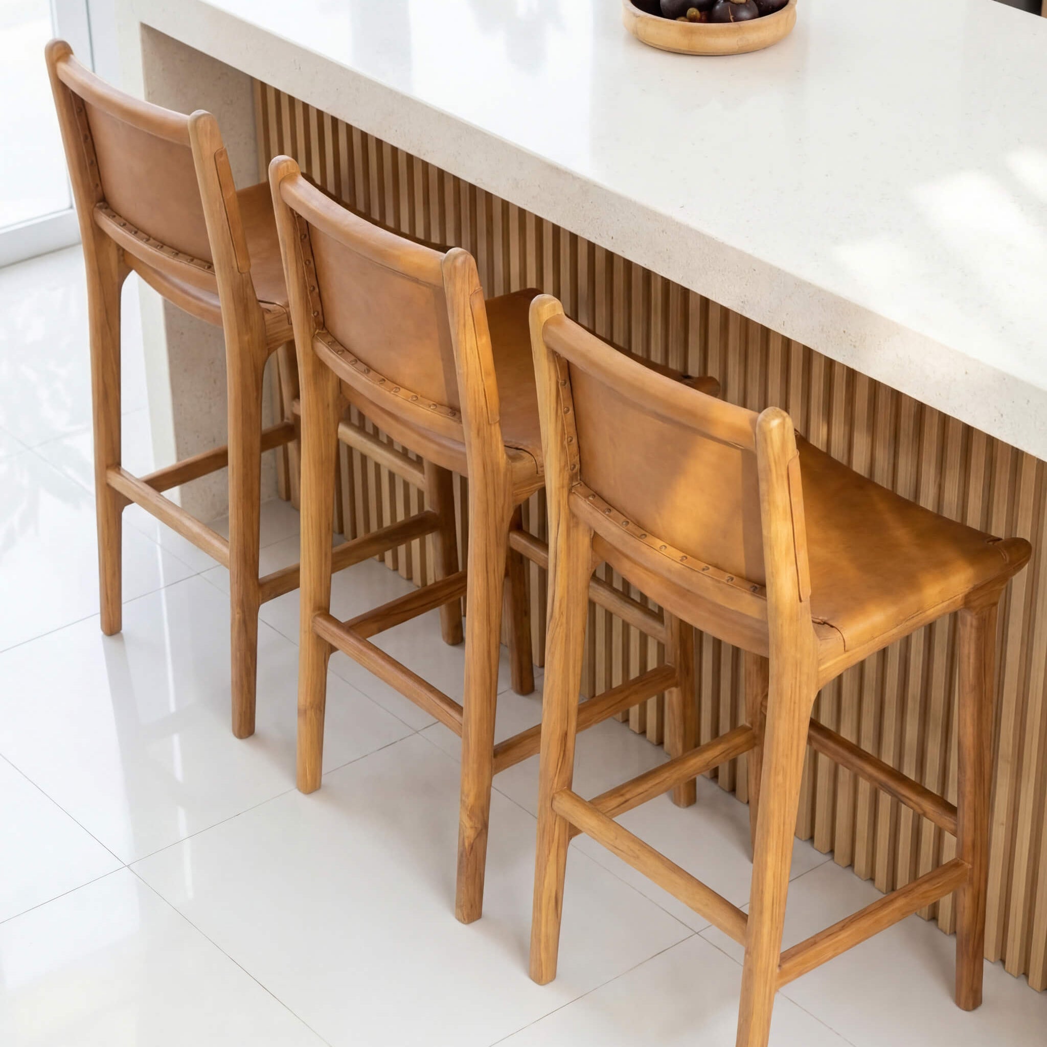 Three wooden bar stools in a kitchen setting with a white countertop.