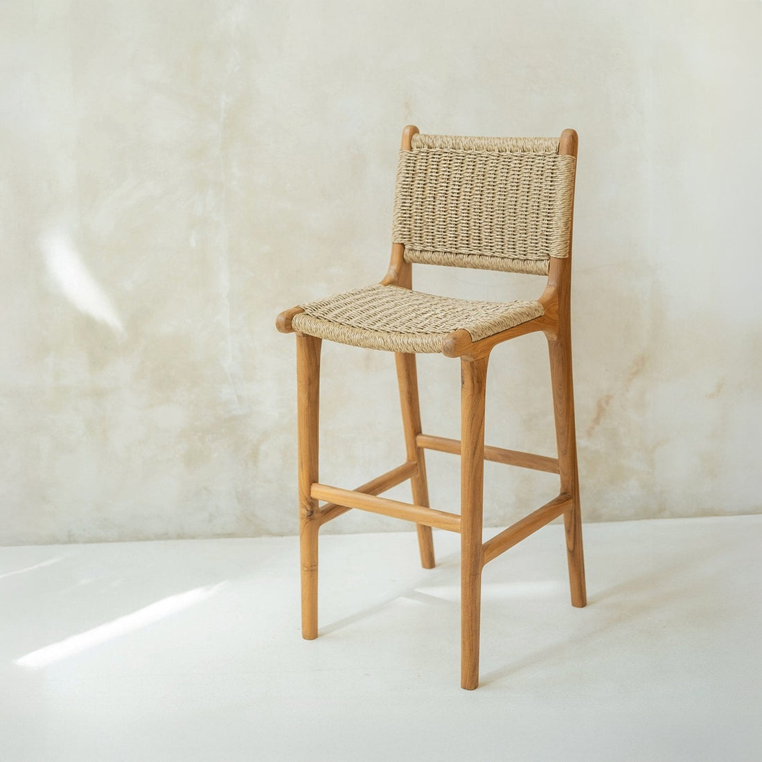 Woven bar stool against a light marble wall