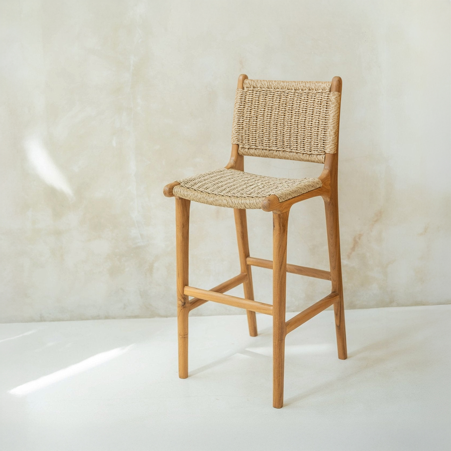 Woven rattam bar stool against a light beige wall